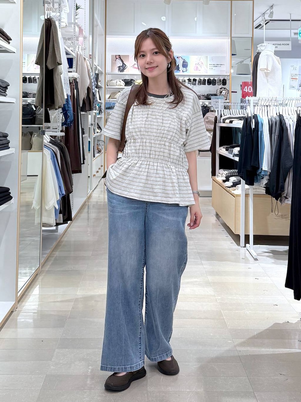 ブルー系のデニムパンツ、ブラウン系のスニーカー、ホワイト系のTシャツ/カットソーを着用したレディースの夏コーディネートの4枚目の写真