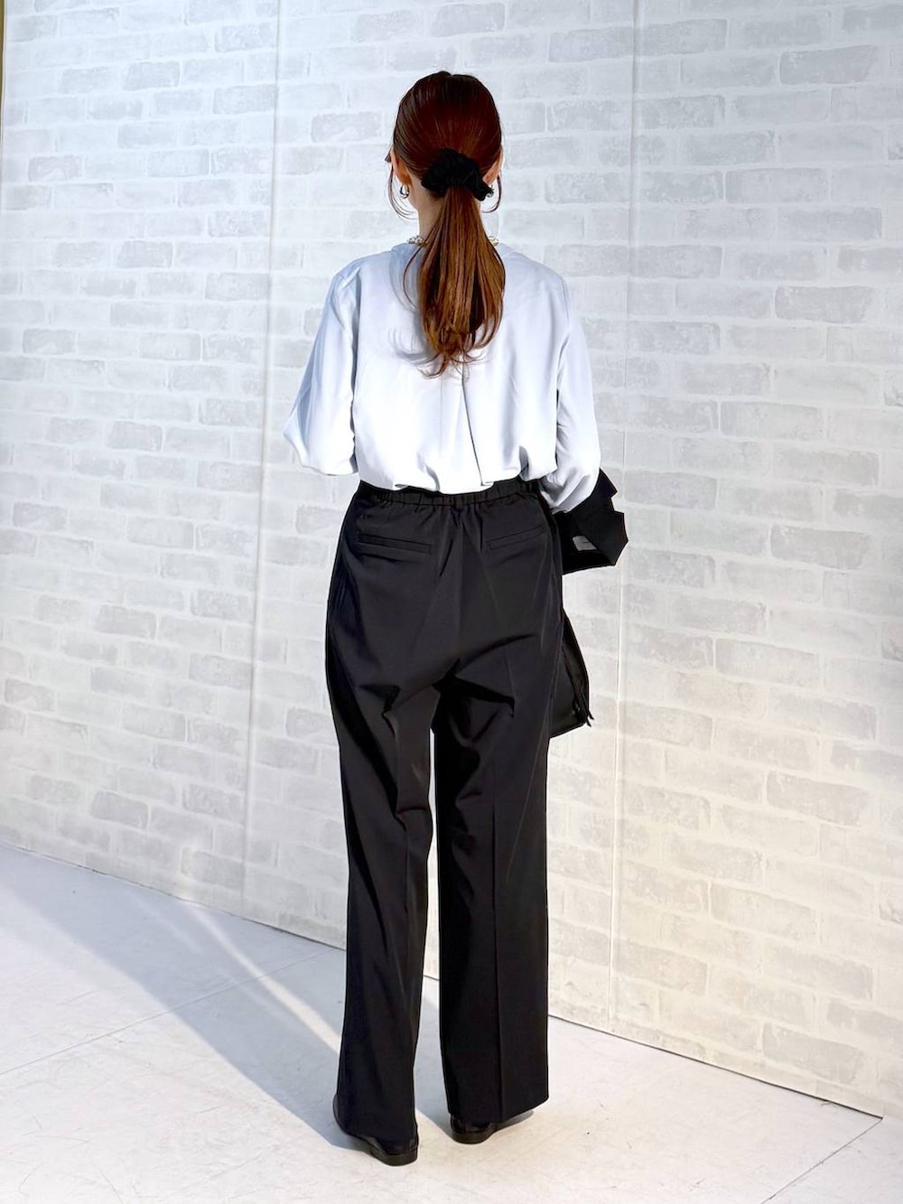 ブラック系のローファー、ブラック系のショルダーバッグ、ブルー系のスラックスを着用したレディースの冬コーディネートの3枚目の写真