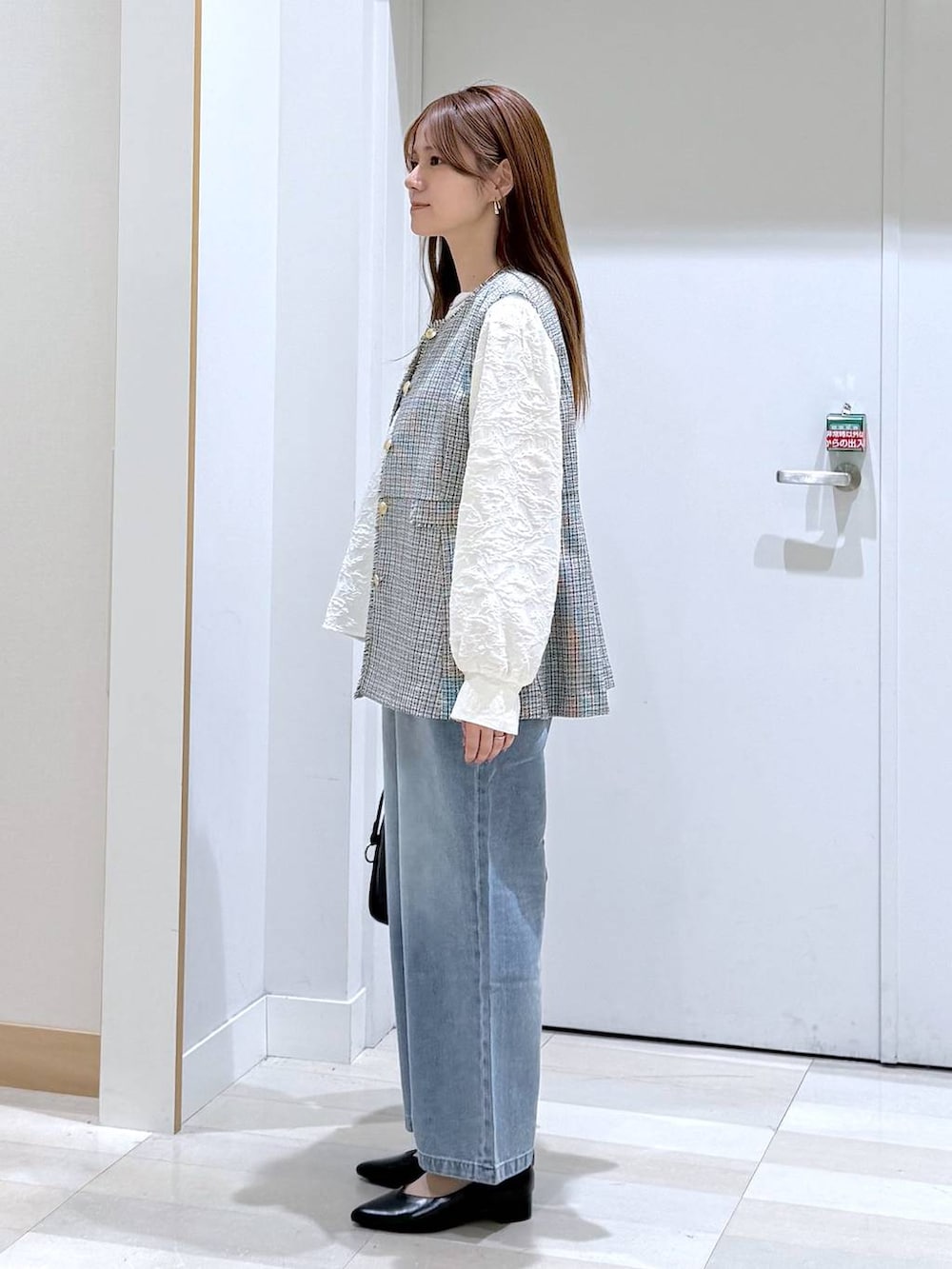 ブルー系のデニムパンツ、ブラック系のパンプス、ブラック系のトートバッグを着用したレディースの春コーディネートの2枚目の写真