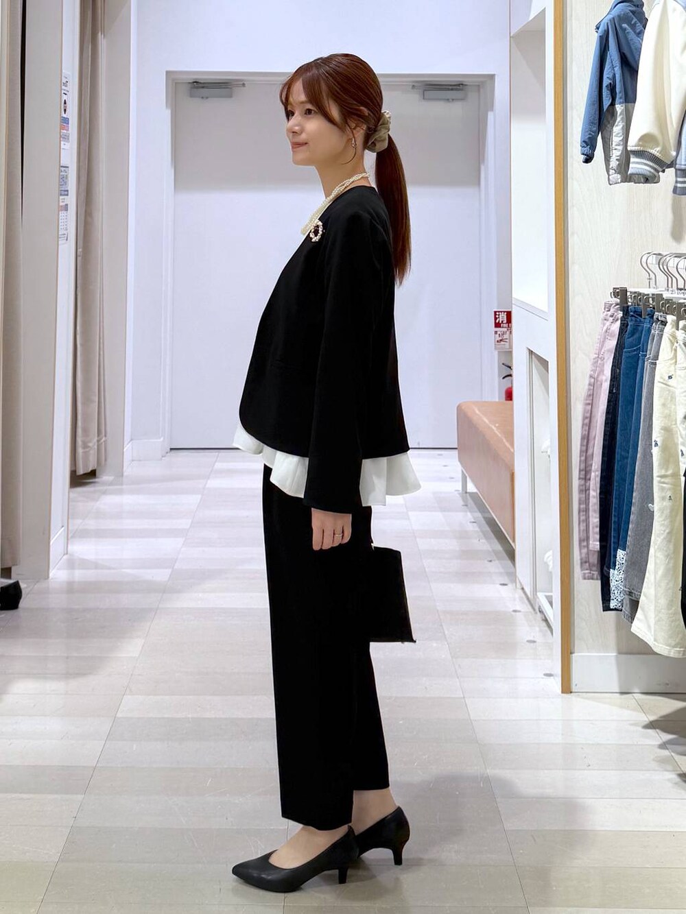 ブラック系のパンプス、ブラック系のセットアップ、ブラック系のショルダーバッグを着用したレディースの冬コーディネートの2枚目の写真