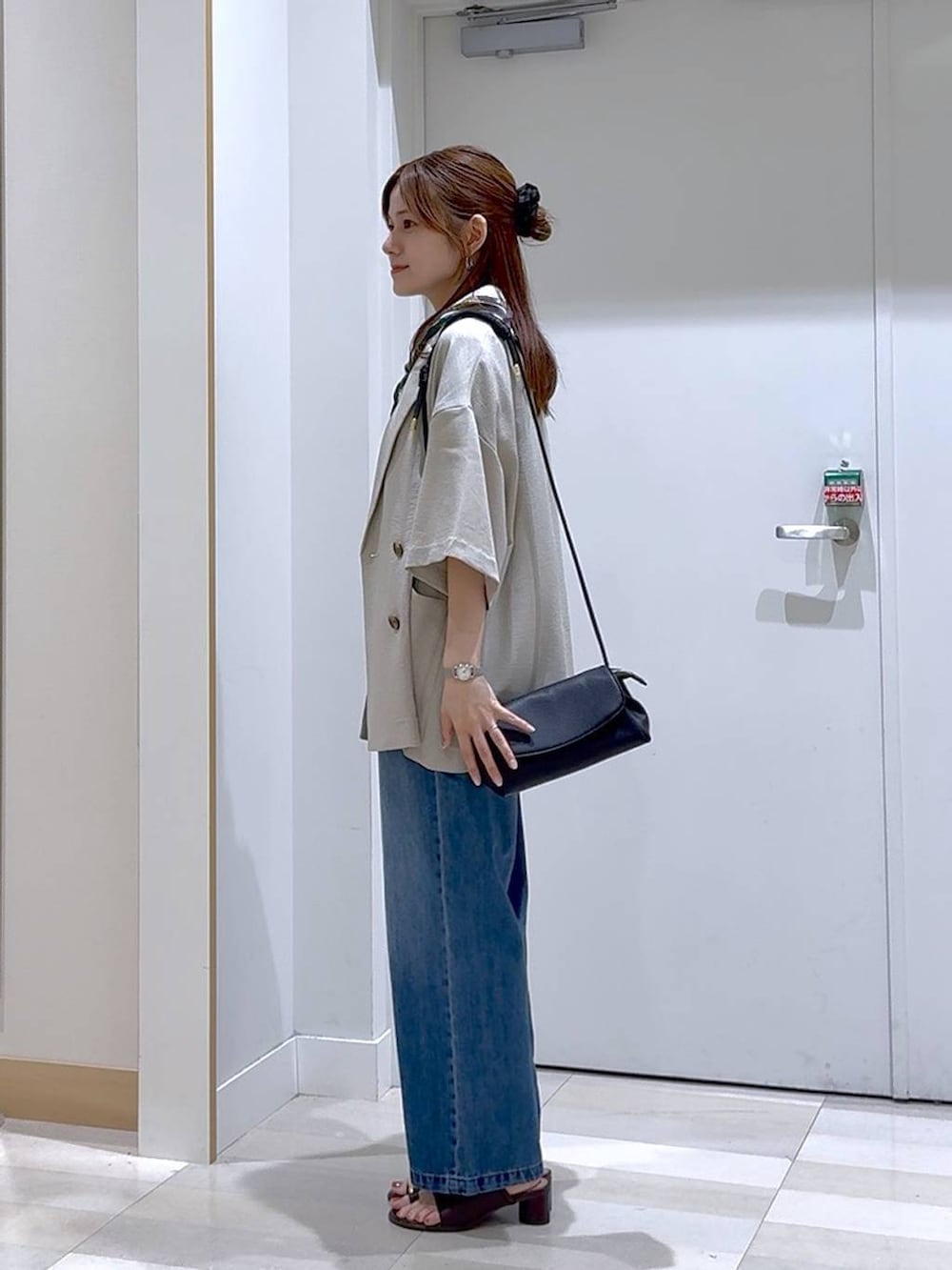 ブルー系のデニムパンツ、ブラック系のショルダーバッグ、ベージュ系のテーラードジャケットを着用したレディースの夏コーディネートの2枚目の写真