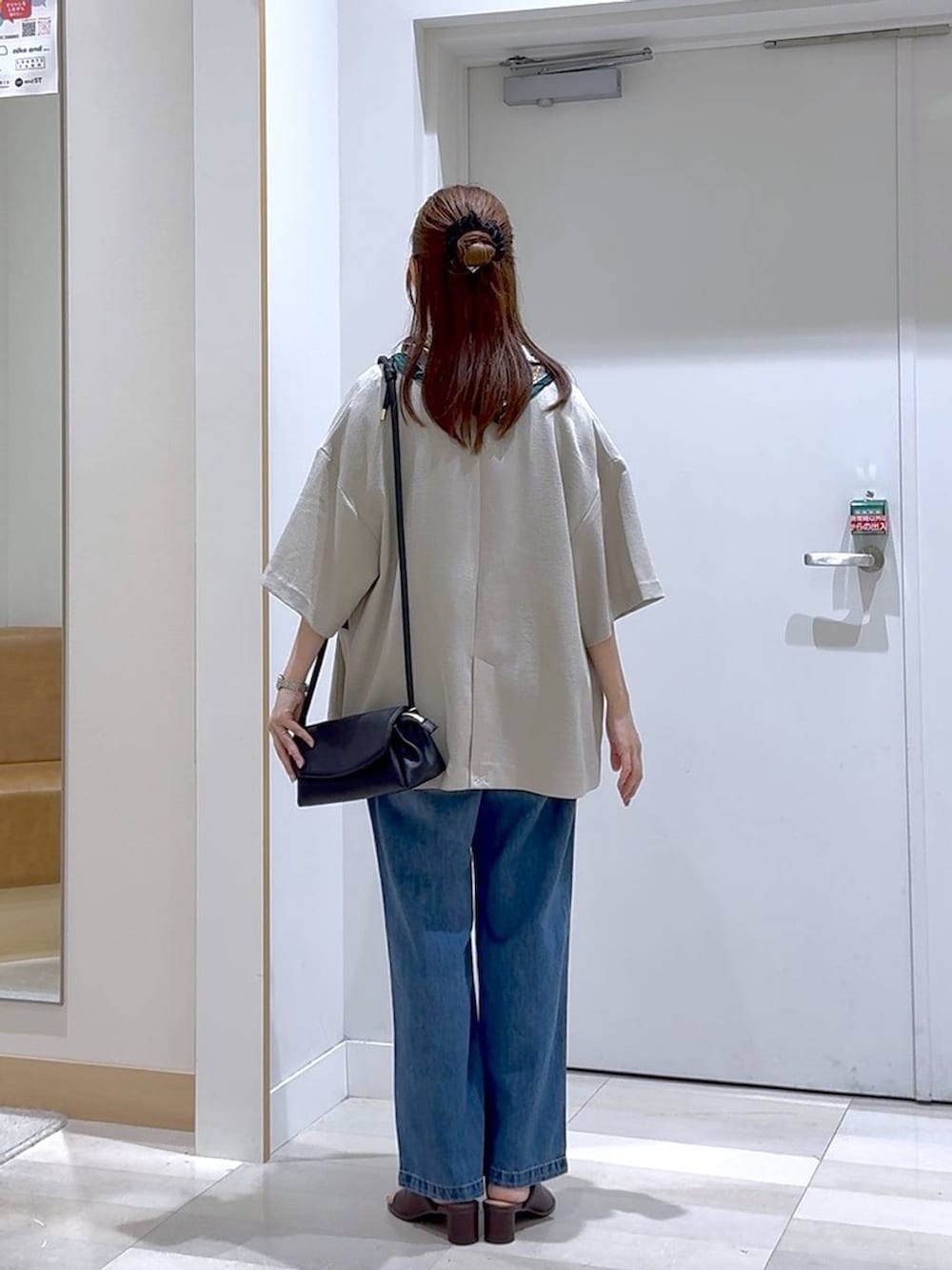 ブルー系のデニムパンツ、ブラック系のショルダーバッグ、ベージュ系のテーラードジャケットを着用したレディースの夏コーディネートの3枚目の写真