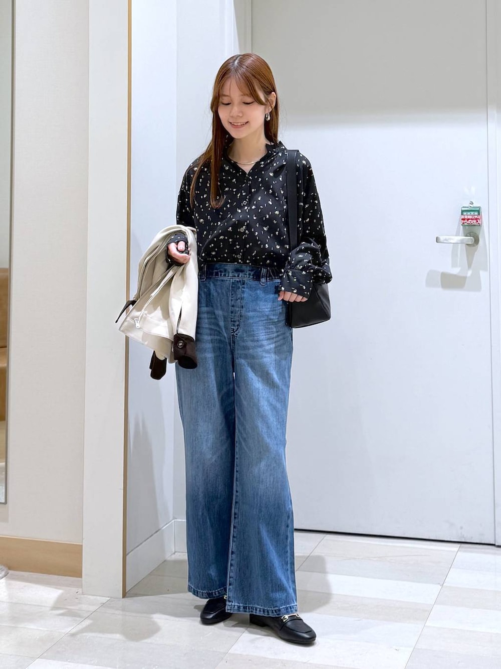 ブラック系のローファー、ブルー系のデニムパンツ、ブラック系のショルダーバッグを着用したレディースの春コーディネートの4枚目の写真