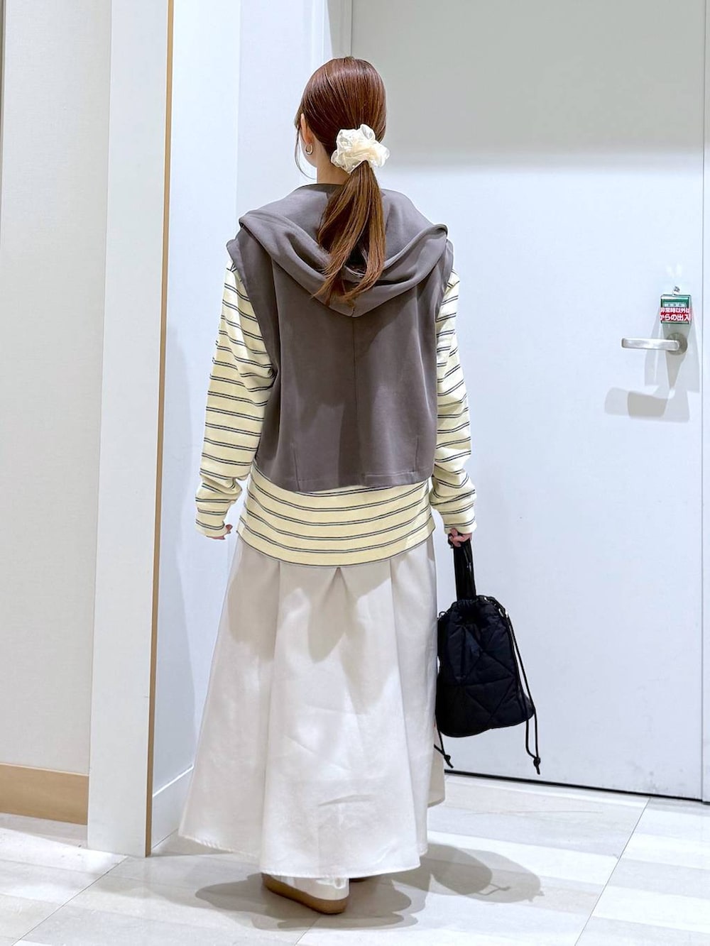 ホワイト系のスニーカー、ブラック系のハンドバッグ、ベージュ系のスカートを着用したレディースの春コーディネートの3枚目の写真