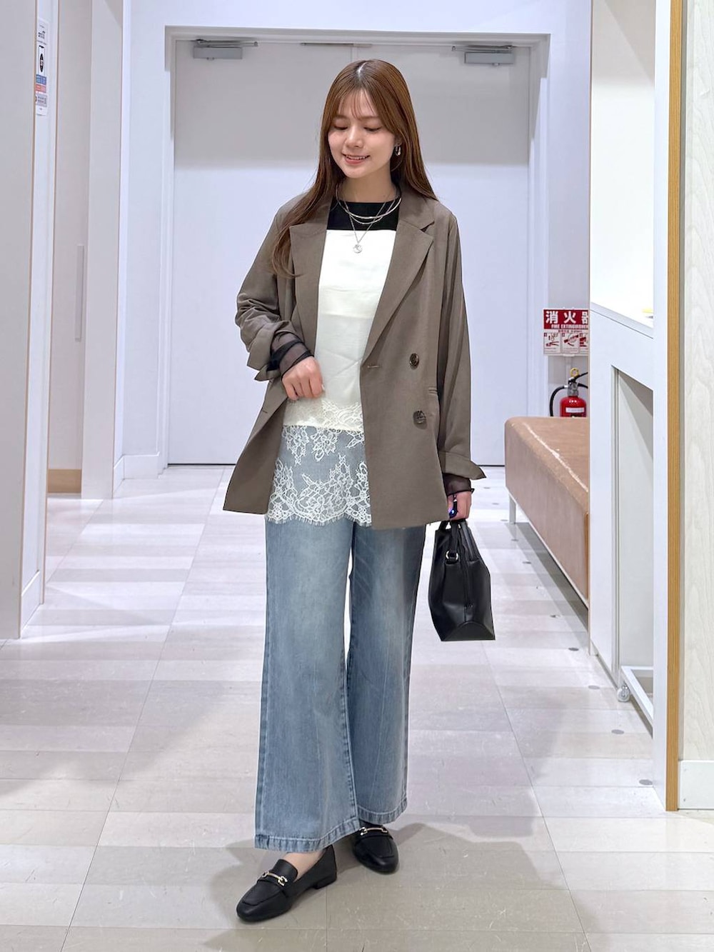 ブラック系のローファー、ブラック系のショルダーバッグ、ブルー系のデニムパンツを着用したレディースの春コーディネートの5枚目の写真