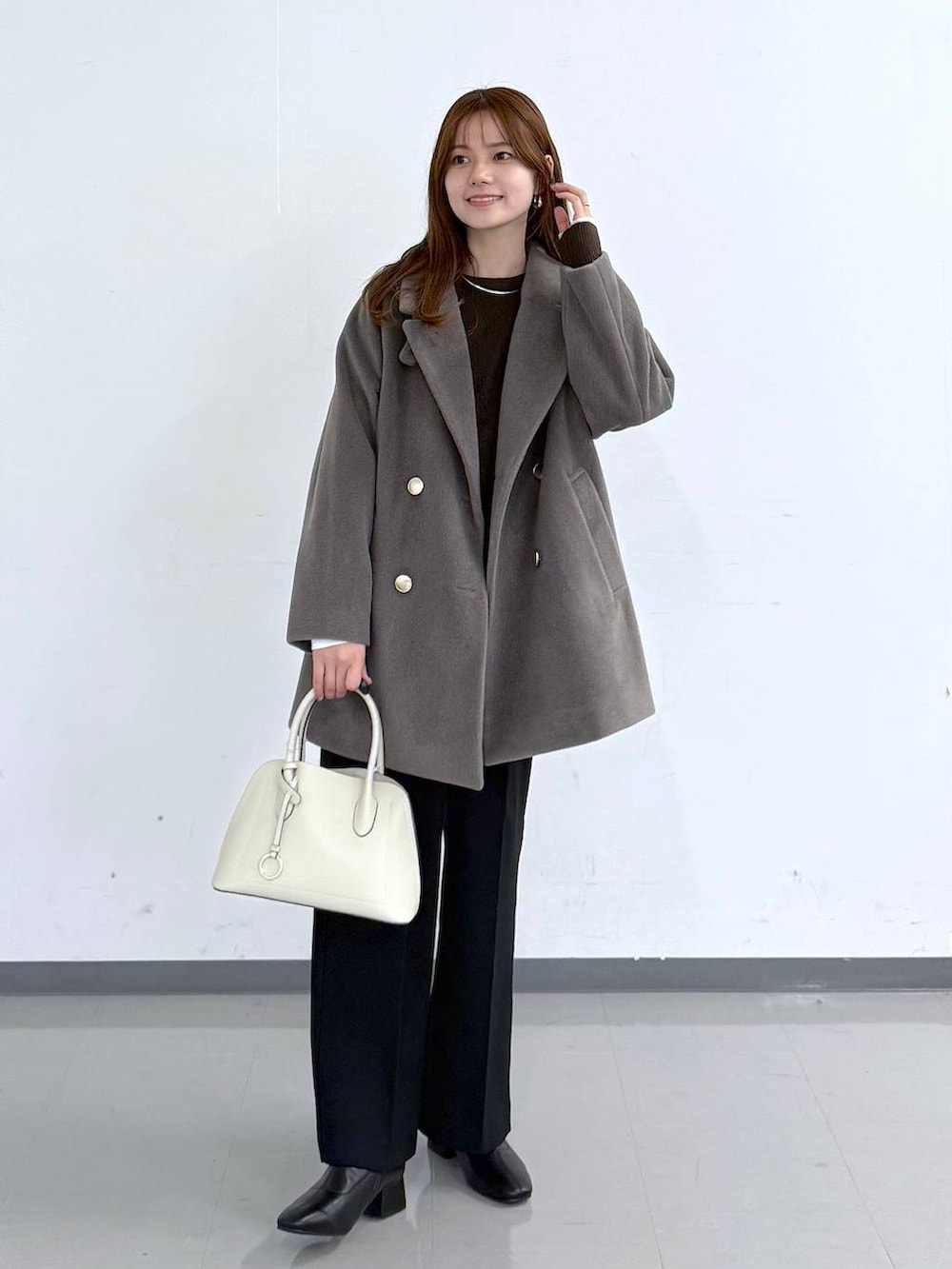 ホワイト系のショルダーバッグ、ブラウン系のチェスターコート、ブラウン系のニット/セーターを着用したレディースの冬コーディネートの5枚目の写真