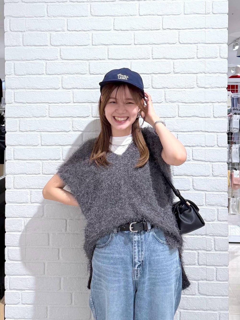 ブルー系のデニムパンツ、ホワイト系のTシャツ/カットソー、ブラック系のショルダーバッグを着用したレディースの秋コーディネートの5枚目の写真