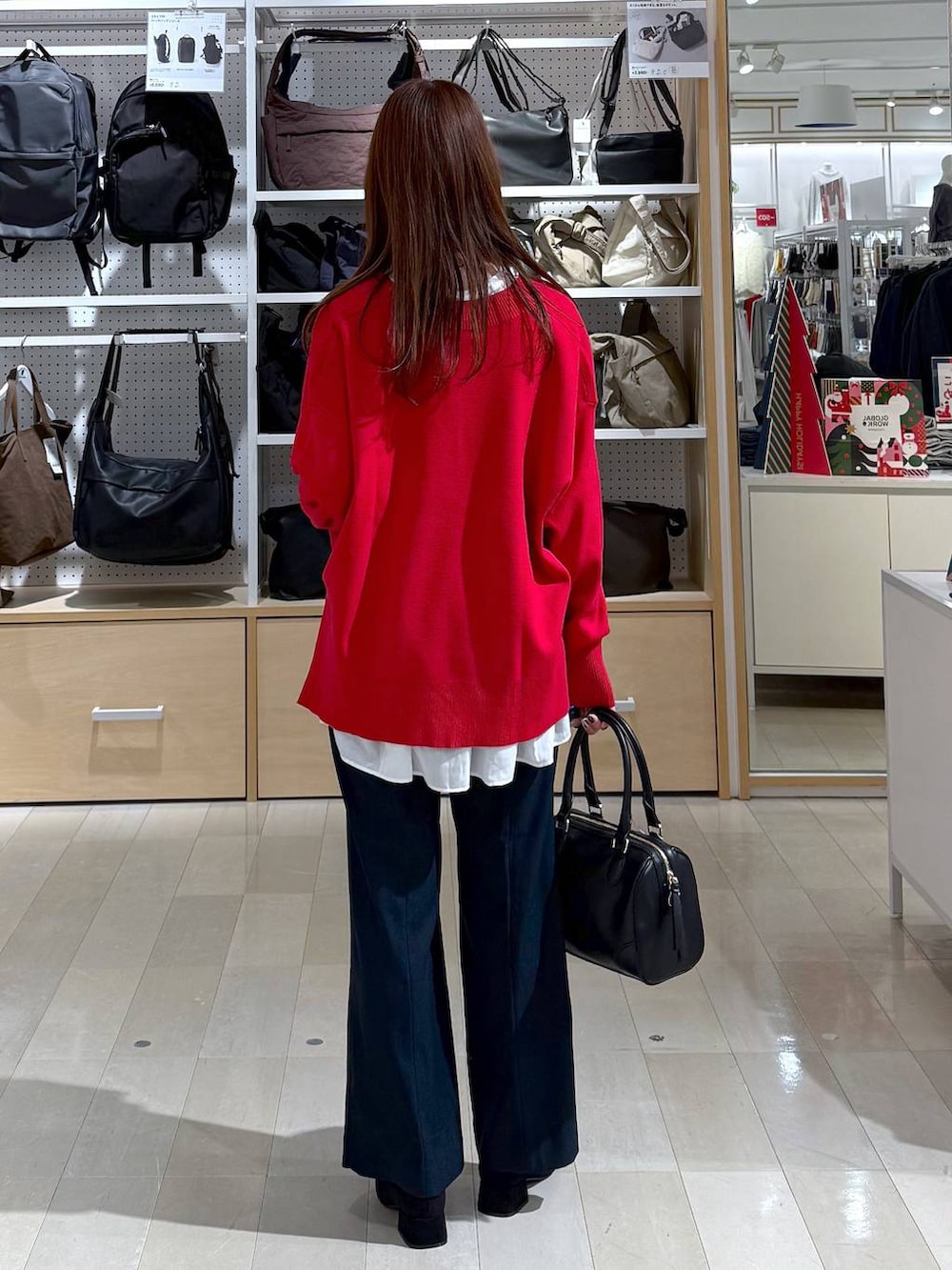 ブラック系のダウンジャケット/コート、レッド系のニット/セーター、ブルー系のその他パンツを着用したレディースの冬コーディネートの3枚目の写真