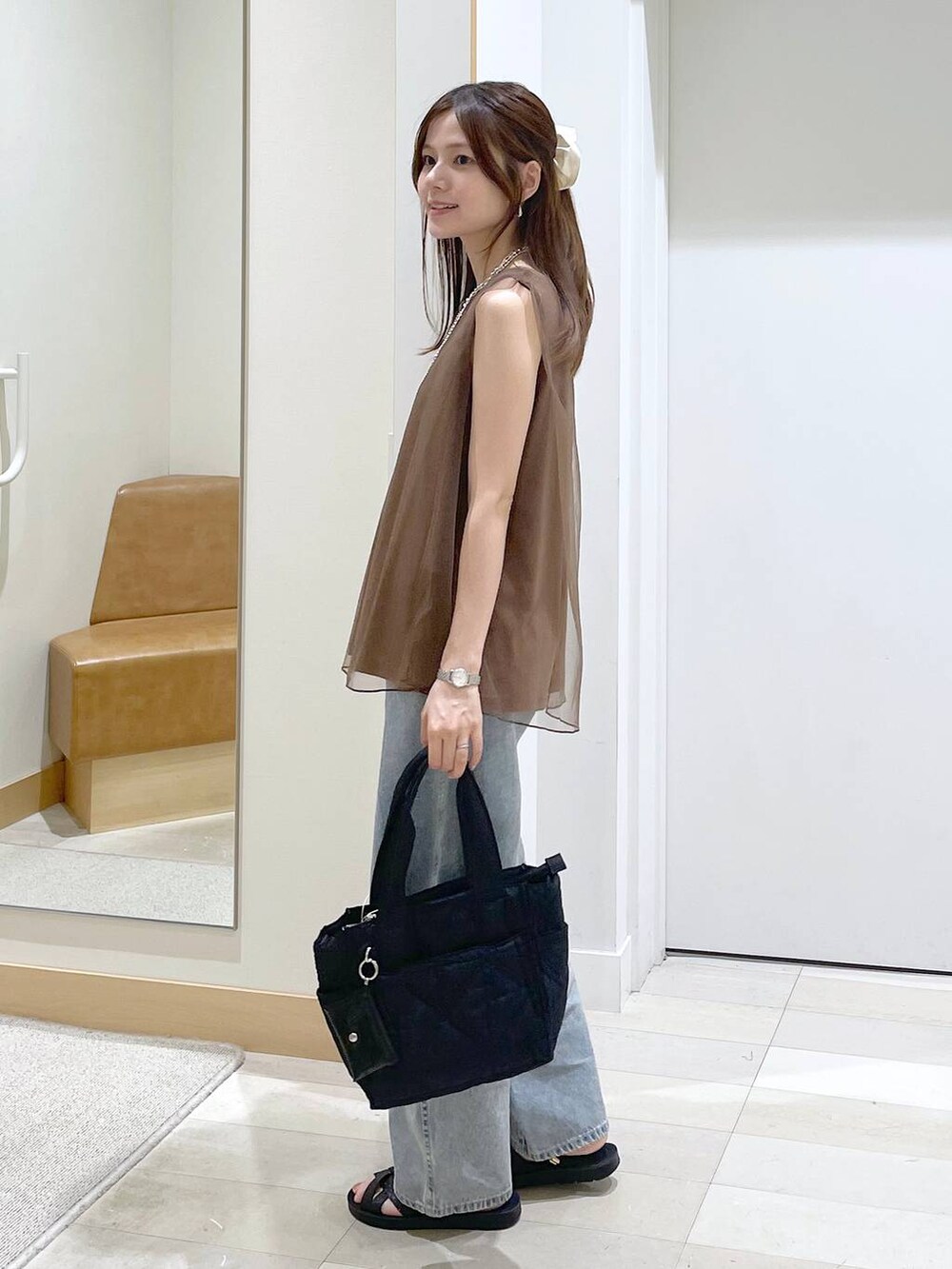 ブラック系のサンダル、ブラック系のトートバッグ、ブルー系のデニムパンツを着用したレディースの夏コーディネートの2枚目の写真