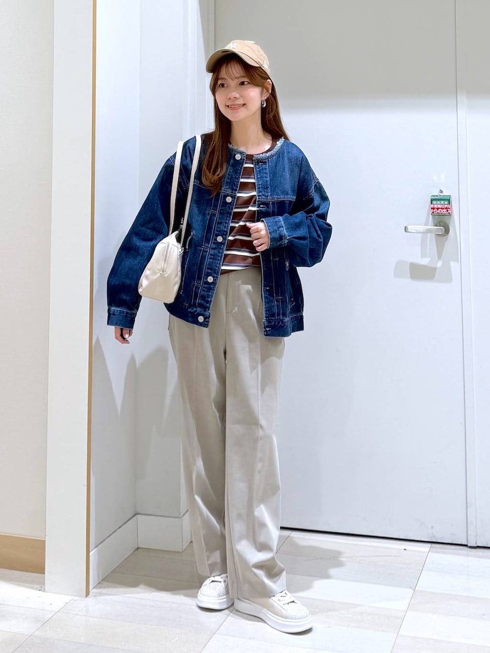 ベージュ系のスラックス、ブルー系のデニムジャケット、ベージュ系のショルダーバッグを着用したレディースの冬コーディネートの5枚目の写真