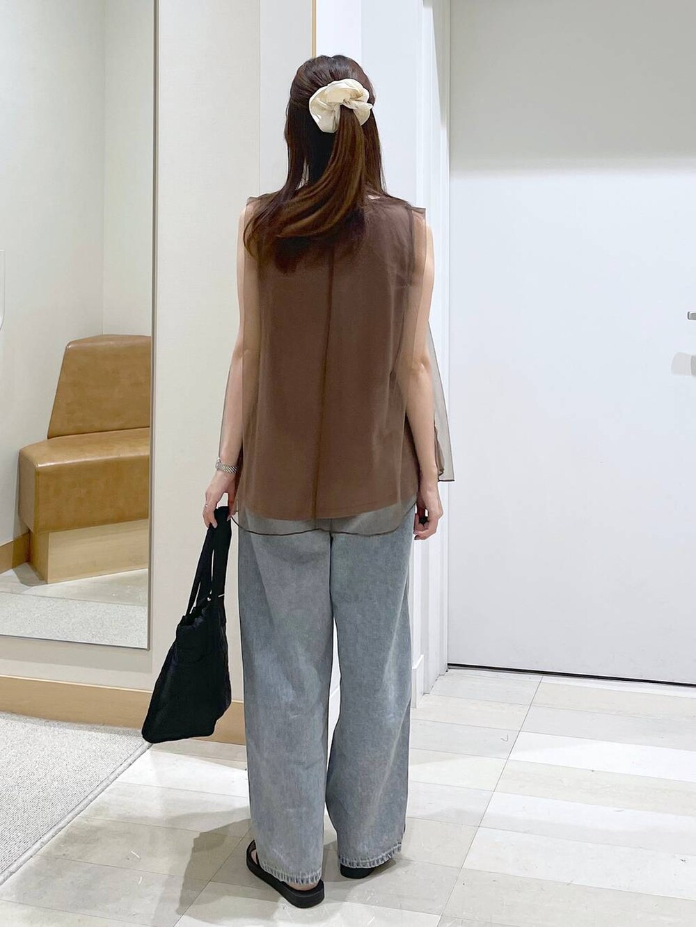 ブラック系のサンダル、ブラック系のトートバッグ、ブルー系のデニムパンツを着用したレディースの夏コーディネートの3枚目の写真