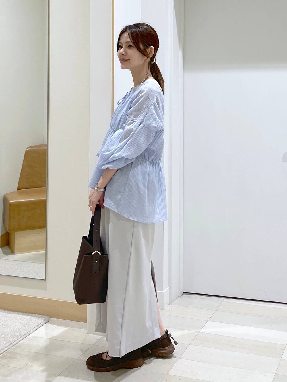 ブラウン系のショルダーバッグ、グレー系のスカート、ブルー系のシャツ/ブラウスを着用したレディースの夏コーディネートの2枚目の写真