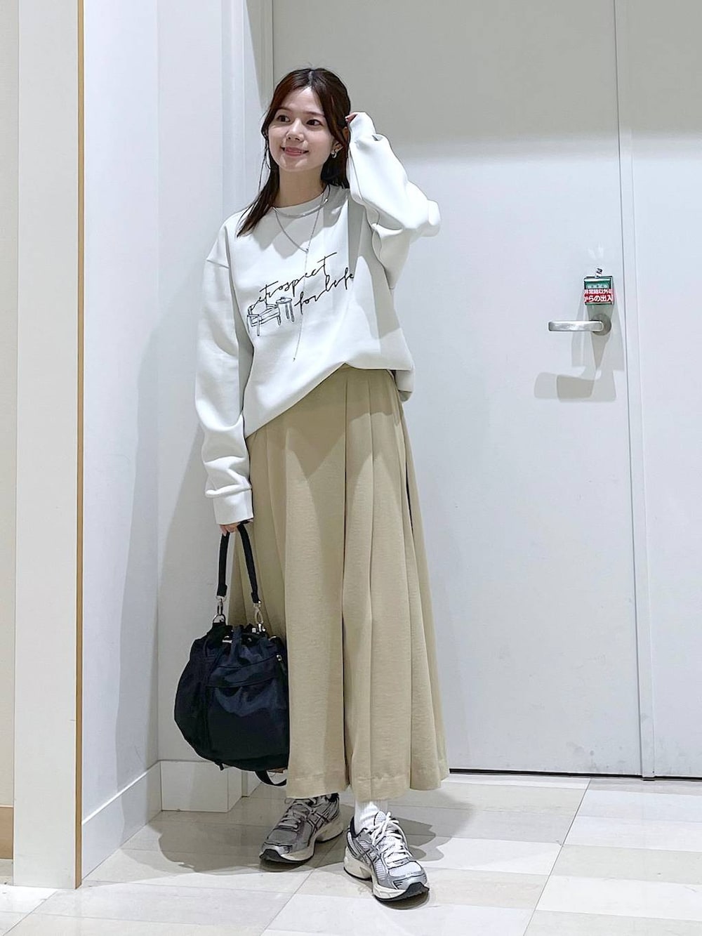 ホワイト系のスウェット、ブラック系のショルダーバッグ、ベージュ系のスカートを着用したレディースの春コーディネートの4枚目の写真