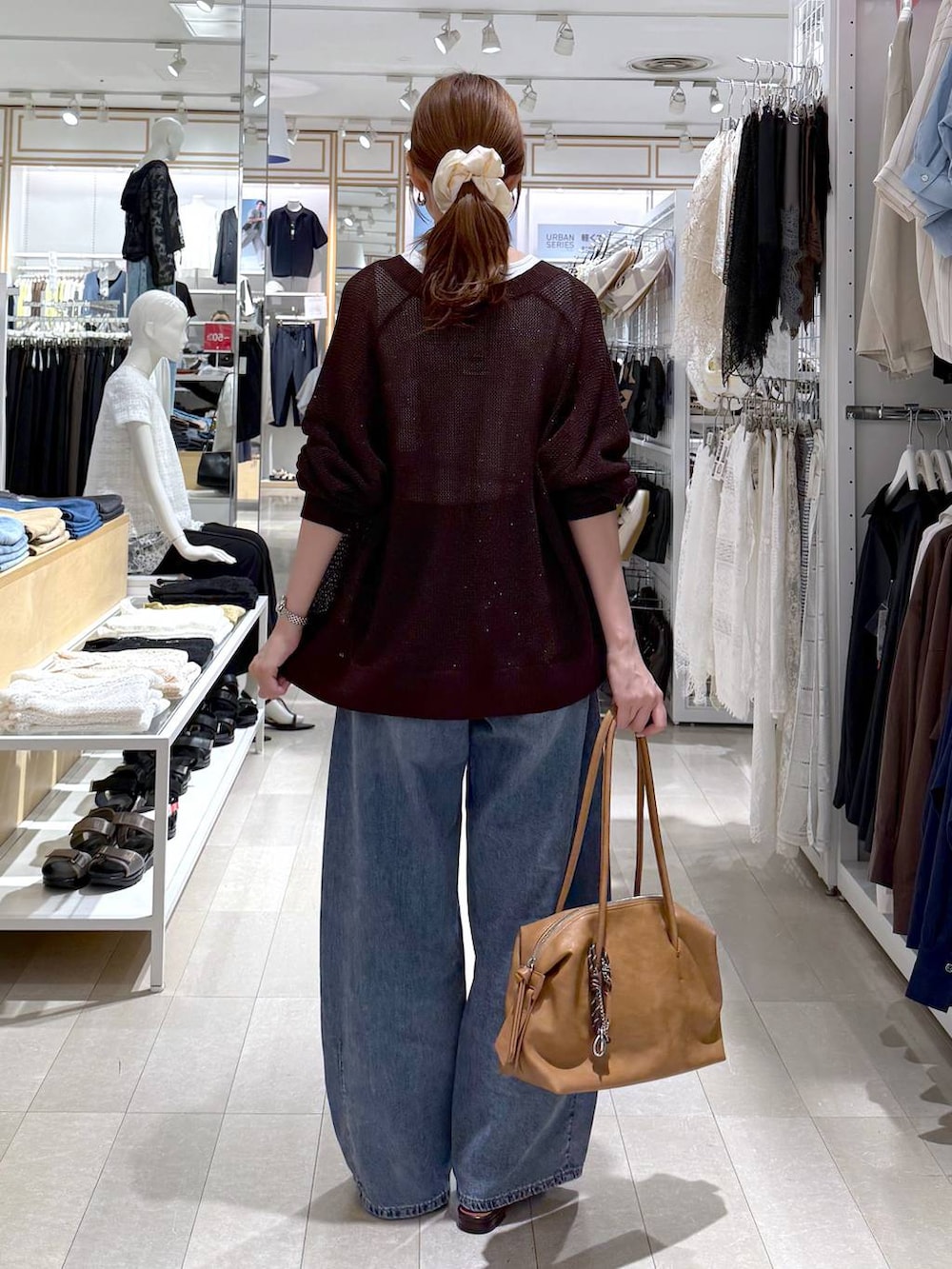 ブラウン系のボストンバッグ、ブルー系のデニムパンツ、ホワイト系のタンクトップを着用したレディースの夏コーディネートの3枚目の写真