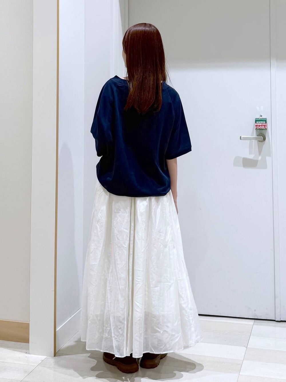 ベージュ系のスカート、ブルー系のTシャツ/カットソー、ゴールド系のネックレスを着用したレディースの秋コーディネートの3枚目の写真