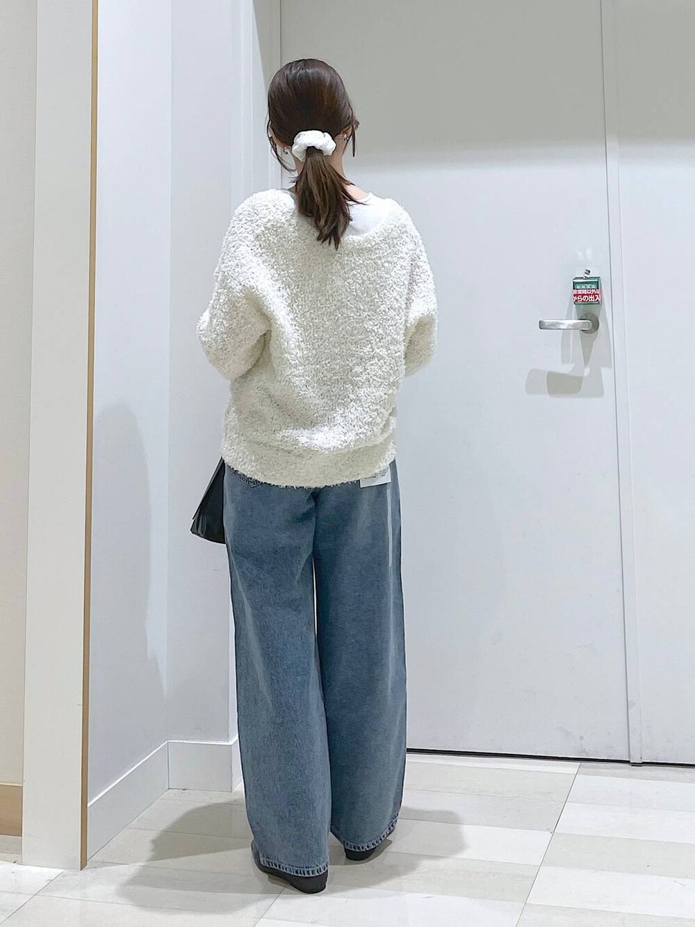 ブルー系のデニムパンツ、ブラック系のパンプス、ブラック系のショルダーバッグを着用したレディースの春コーディネートの3枚目の写真