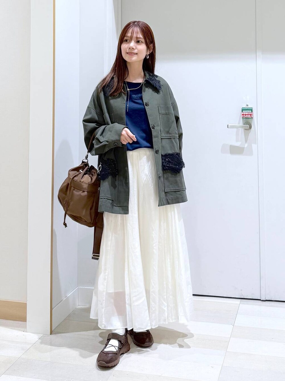 ブラウン系のショルダーバッグ、ベージュ系のスカート、ブルー系のTシャツ/カットソーを着用したレディースの秋コーディネートの5枚目の写真