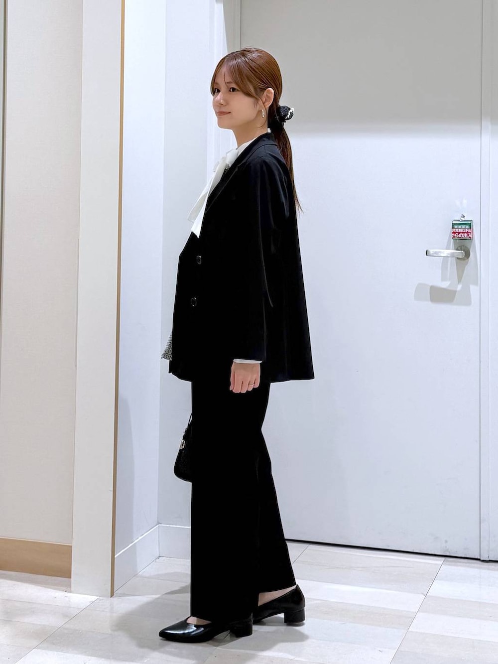 ブラック系のパンプス、ブラック系のトートバッグ、ブラック系のスラックスを着用したレディースの春コーディネートの3枚目の写真