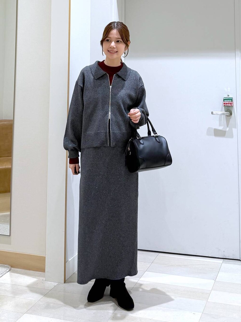 ブラック系のブルゾン、レッド系のニット/セーター、グレー系のワンピースを着用したレディースの秋コーディネートの6枚目の写真