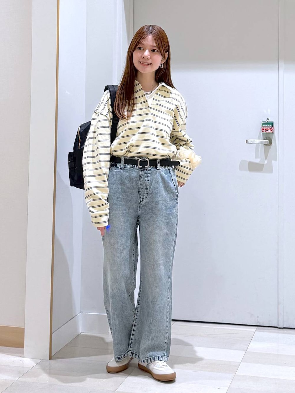 ホワイト系のスニーカー、ブラック系のバックパック/リュック、ブルー系のデニムパンツを着用したレディースの春コーディネートの6枚目の写真