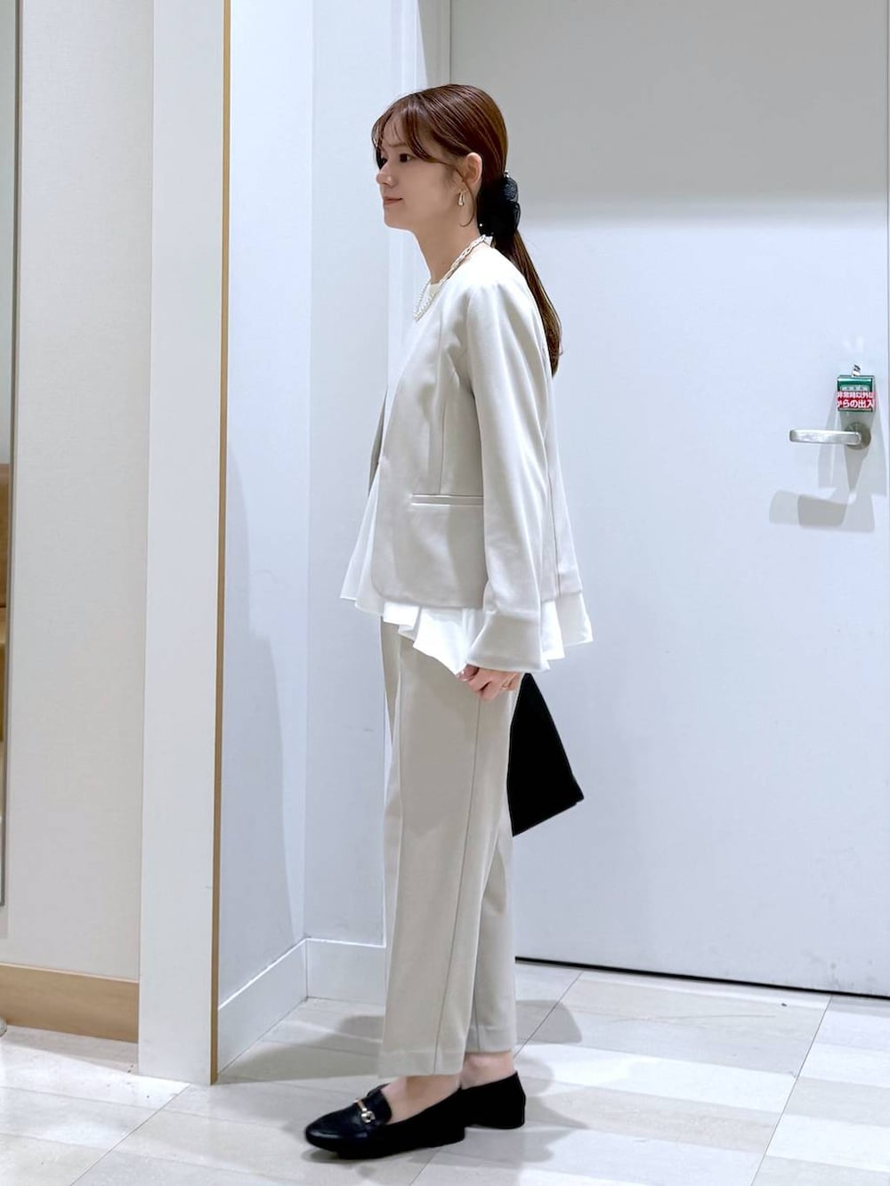 ブラック系のローファー、ブラック系のトートバッグ、ベージュ系のセットアップを着用したレディースの冬コーディネートの2枚目の写真