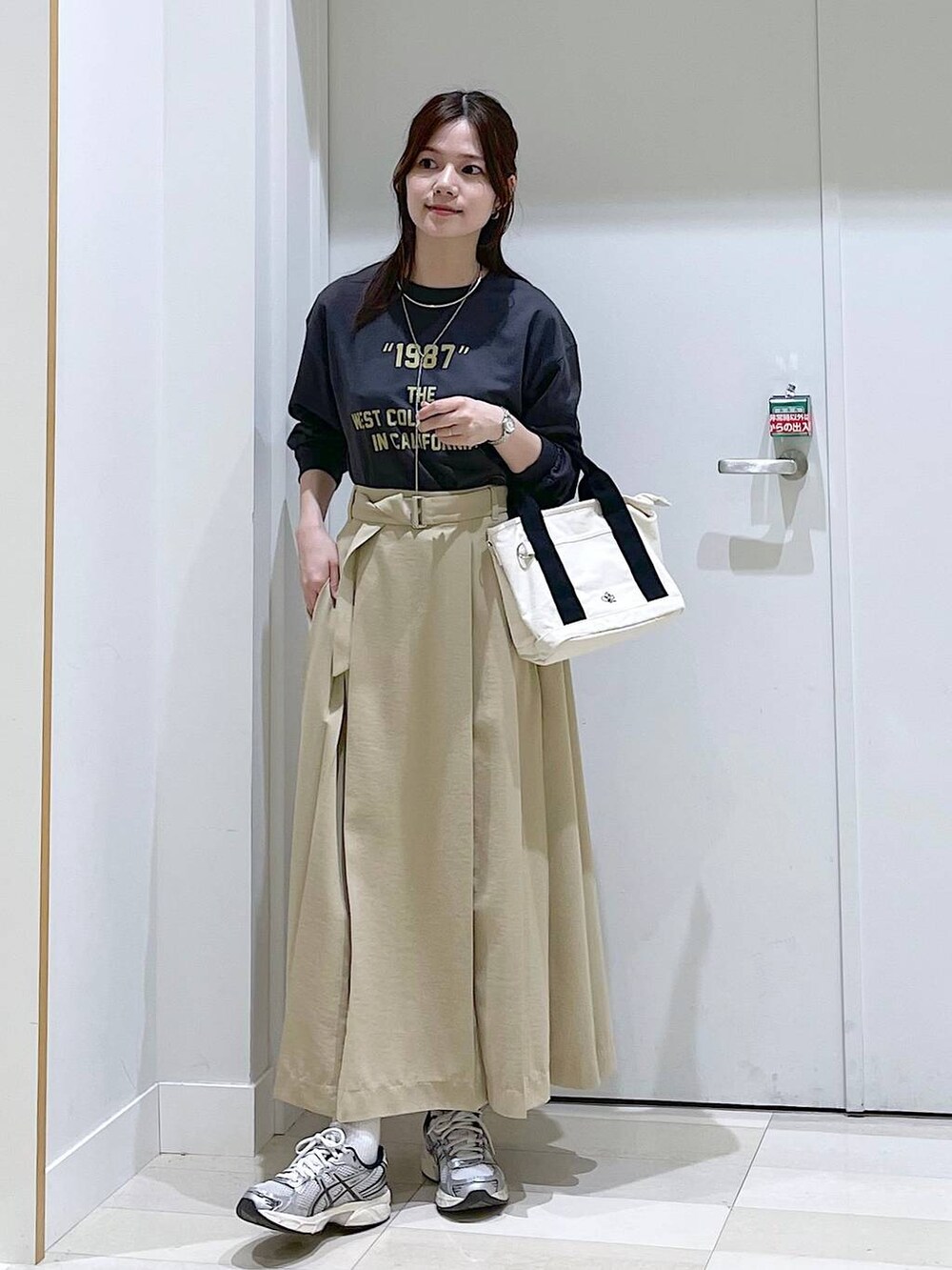 ホワイト系のスウェット、ブラック系のショルダーバッグ、ベージュ系のスカートを着用したレディースの春コーディネートの5枚目の写真