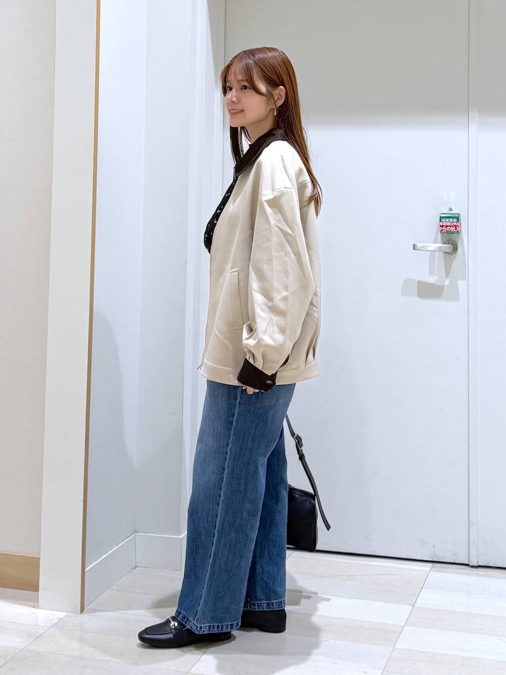 ブラック系のローファー、ブルー系のデニムパンツ、ブラック系のショルダーバッグを着用したレディースの春コーディネートの2枚目の写真