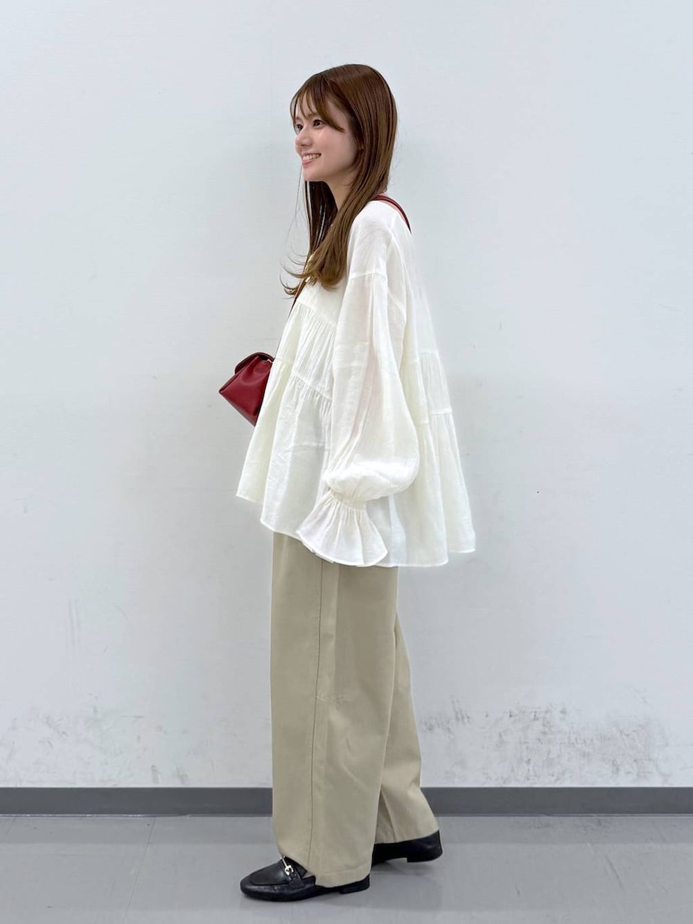 ブラック系のローファー、レッド系のショルダーバッグ、ベージュ系のその他パンツを着用したレディースの春コーディネートの2枚目の写真