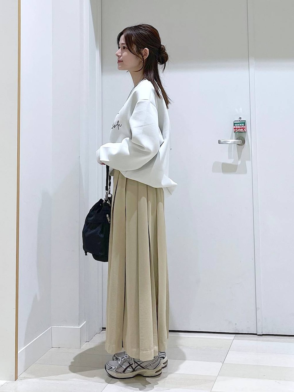 ホワイト系のスウェット、ブラック系のショルダーバッグ、ベージュ系のスカートを着用したレディースの春コーディネートの2枚目の写真