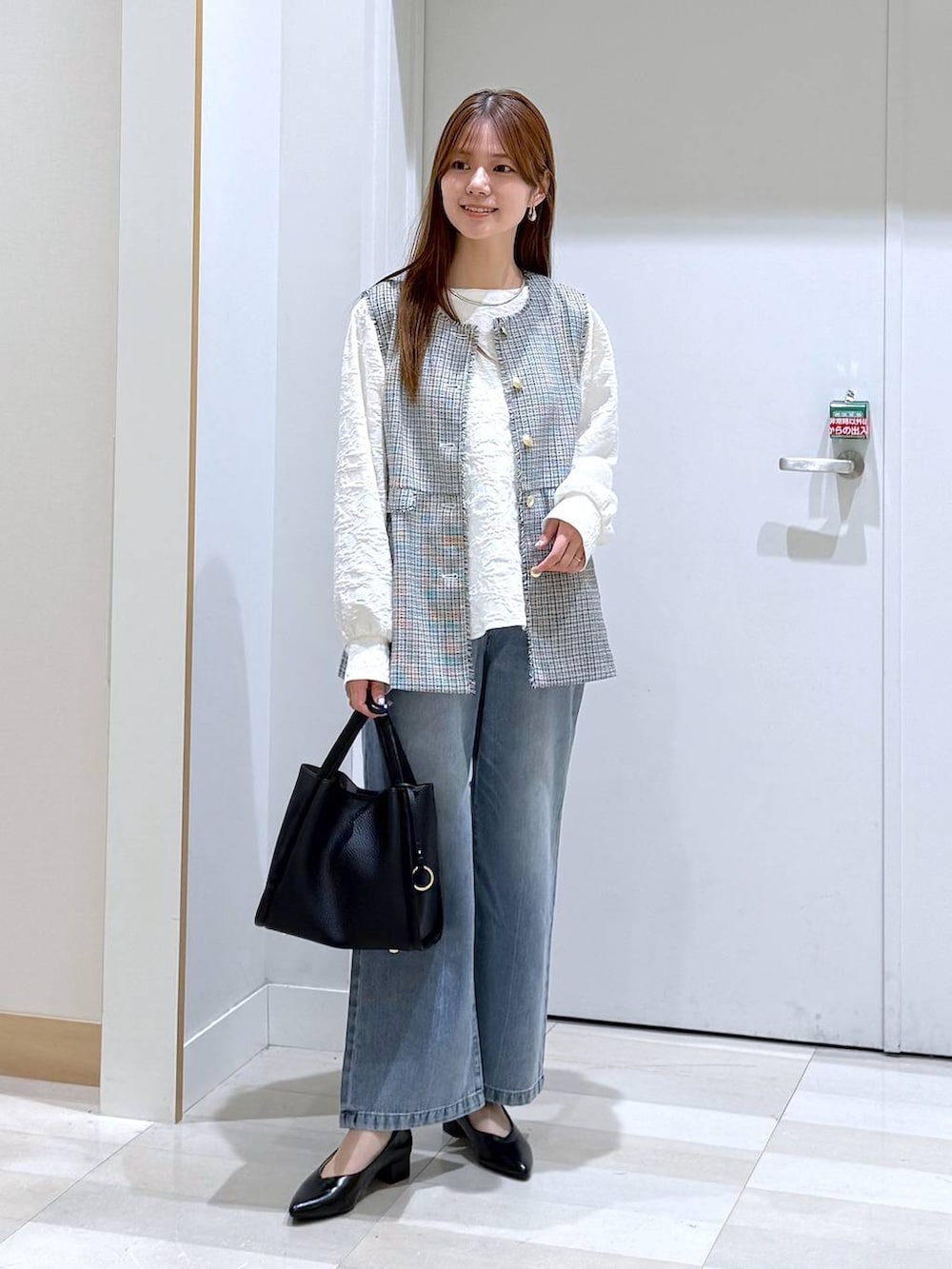 ブルー系のデニムパンツ、ブラック系のパンプス、ブラック系のトートバッグを着用したレディースの春コーディネートの4枚目の写真