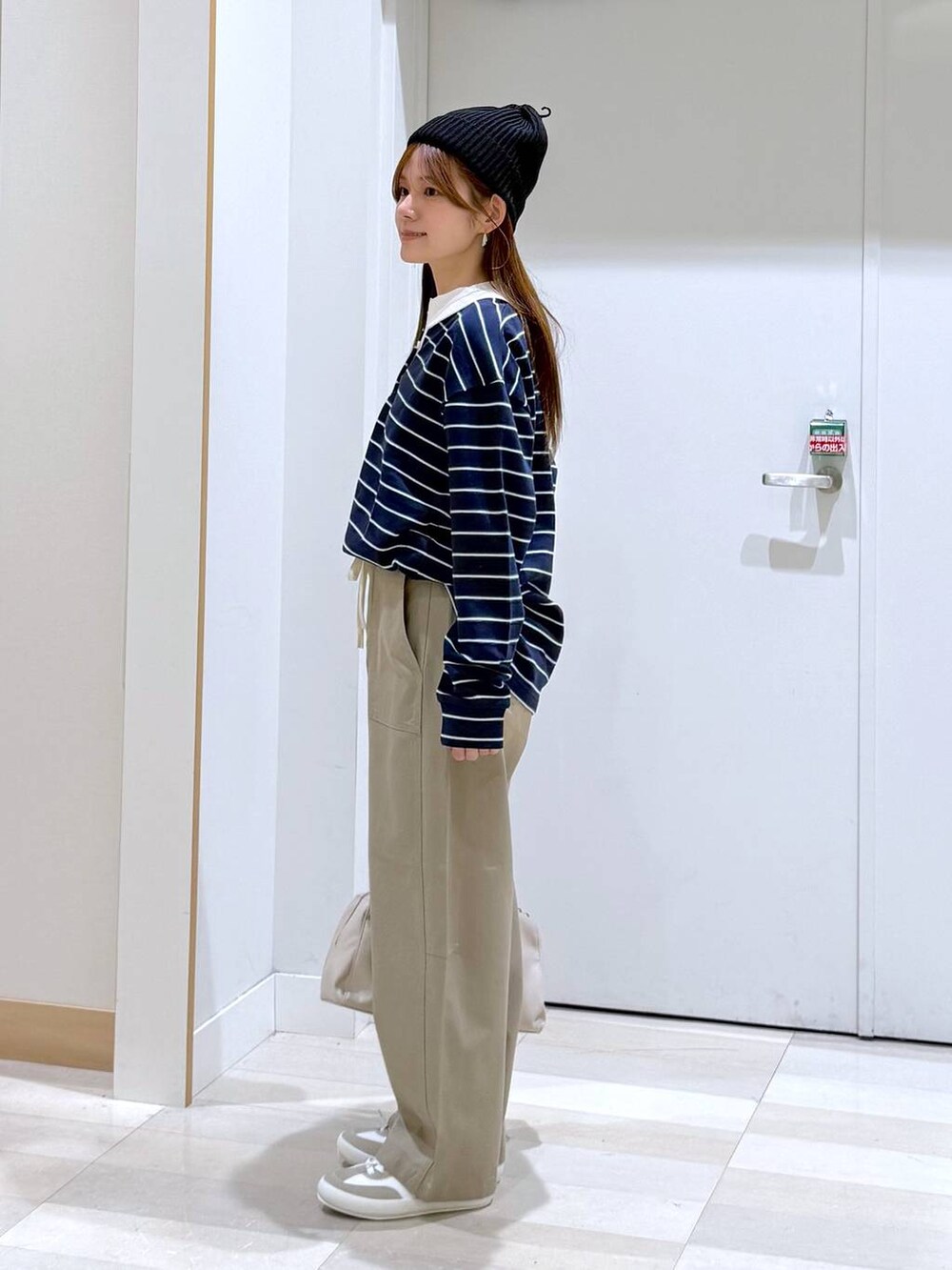 ホワイト系のスニーカー、ブルー系のスウェット、ベージュ系のショルダーバッグを着用したレディースの春コーディネートの2枚目の写真