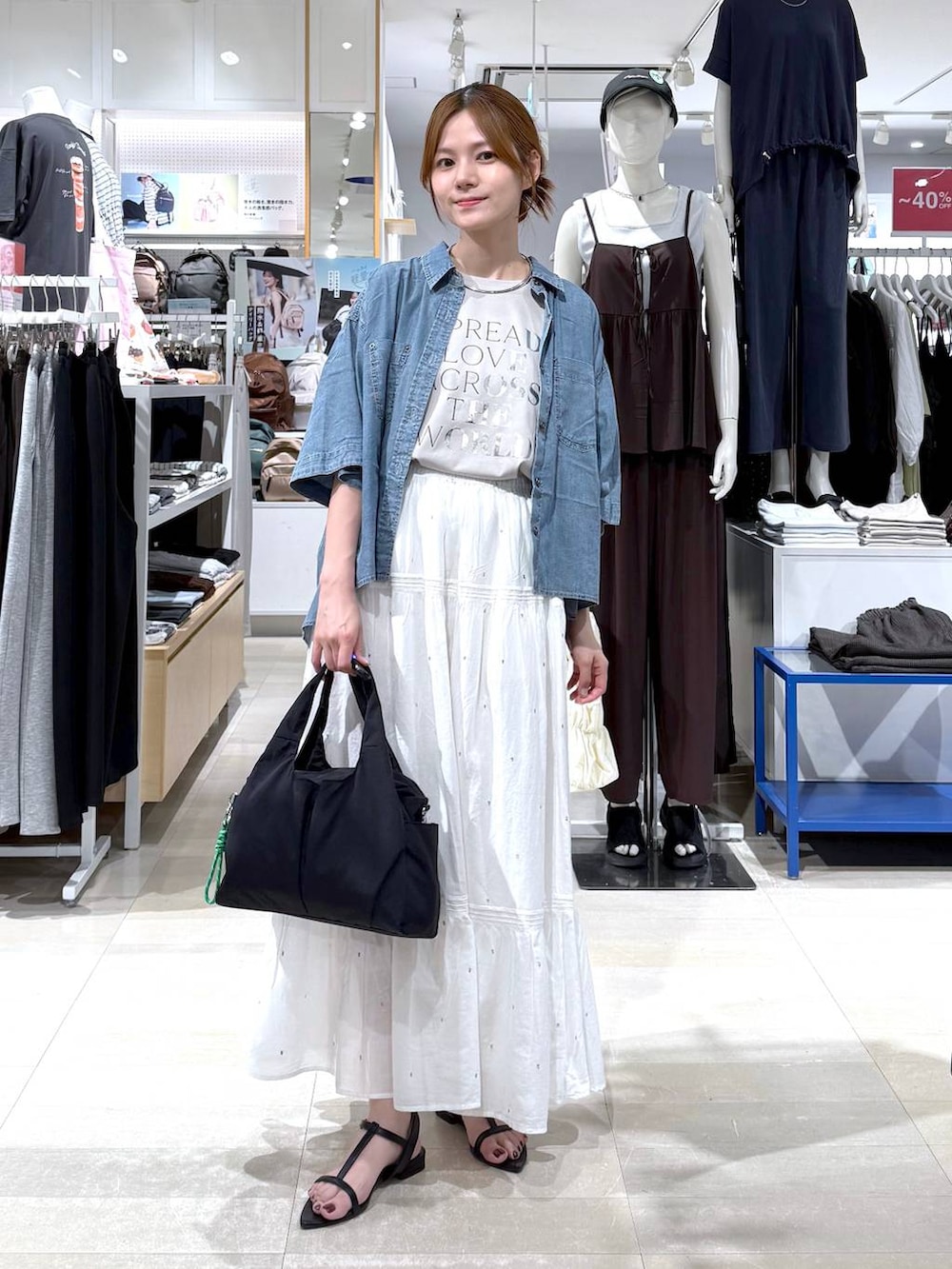 ブラック系のトートバッグ、ホワイト系のスカート、ベージュ系のTシャツ/カットソーを着用したレディースの夏コーディネートの4枚目の写真