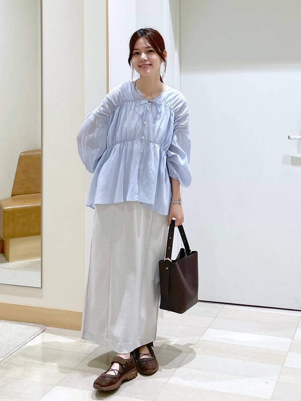 ブラウン系のショルダーバッグ、グレー系のスカート、ブルー系のシャツ/ブラウスを着用したレディースの夏コーディネートの4枚目の写真