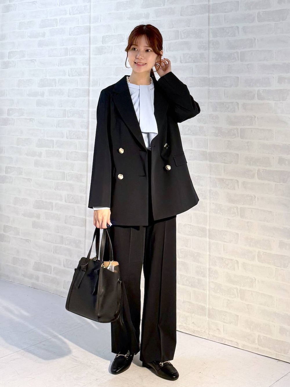 ブラック系のローファー、ブラック系のショルダーバッグ、ブルー系のスラックスを着用したレディースの冬コーディネートの4枚目の写真