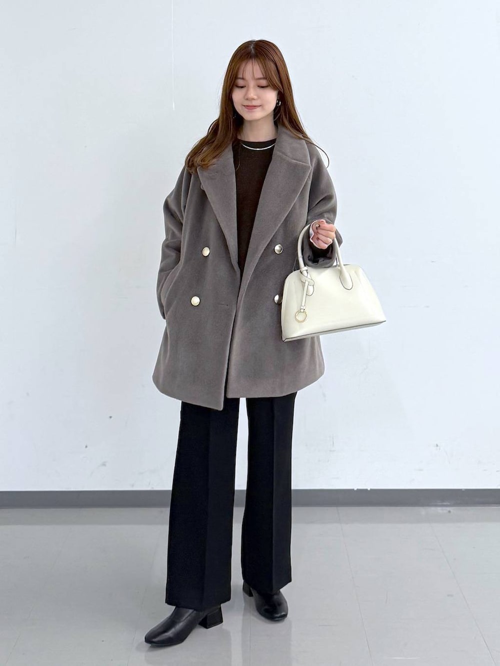 ホワイト系のショルダーバッグ、ブラウン系のチェスターコート、ブラウン系のニット/セーターを着用したレディースの冬コーディネートの4枚目の写真