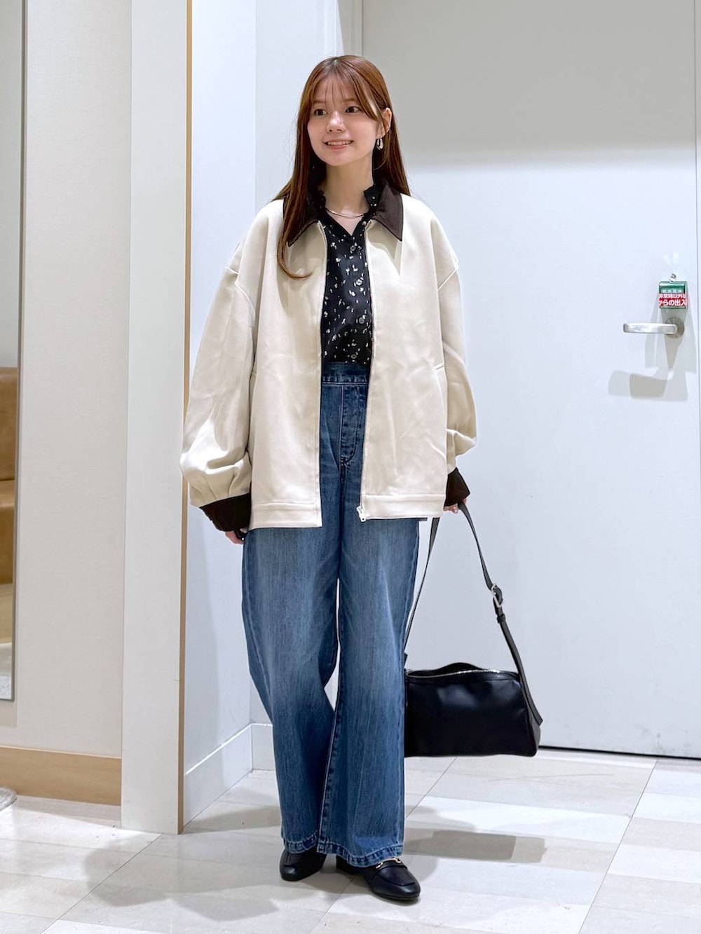 ブラック系のローファー、ブルー系のデニムパンツ、ブラック系のショルダーバッグを着用したレディースの春コーディネートの5枚目の写真