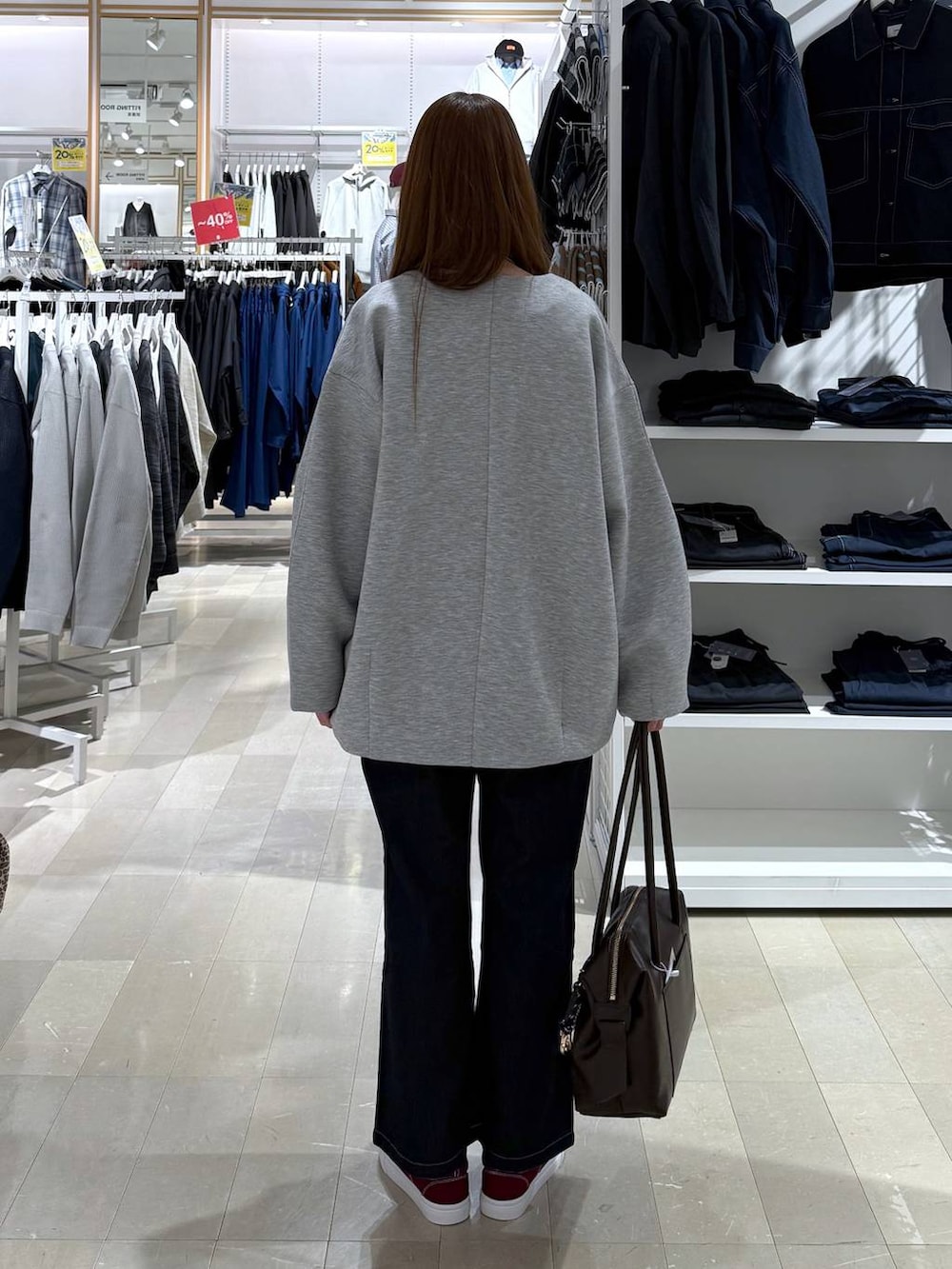 ブラウン系のボストンバッグ、ブルー系のデニムパンツ、グレー系のブルゾンを着用したレディースの春コーディネートの3枚目の写真