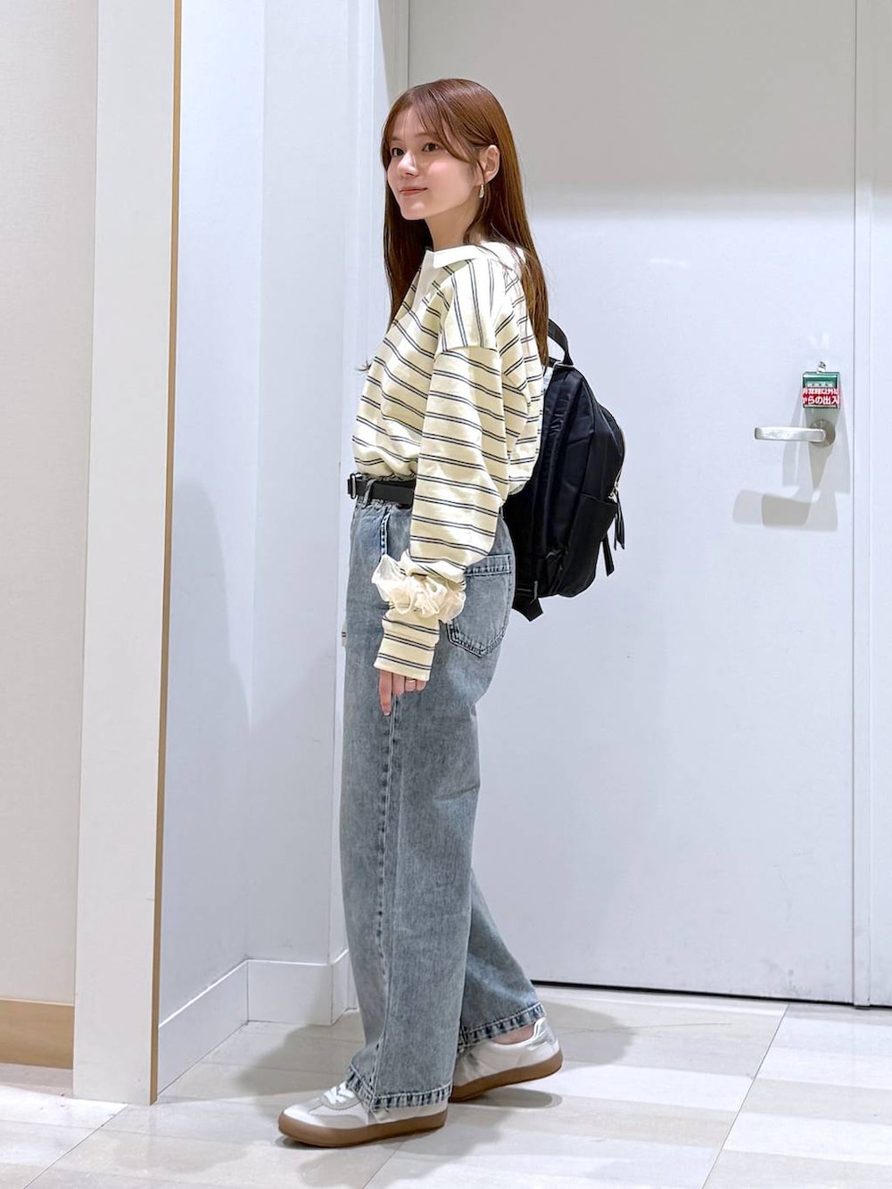 ホワイト系のスニーカー、ブラック系のバックパック/リュック、ブルー系のデニムパンツを着用したレディースの春コーディネートの3枚目の写真