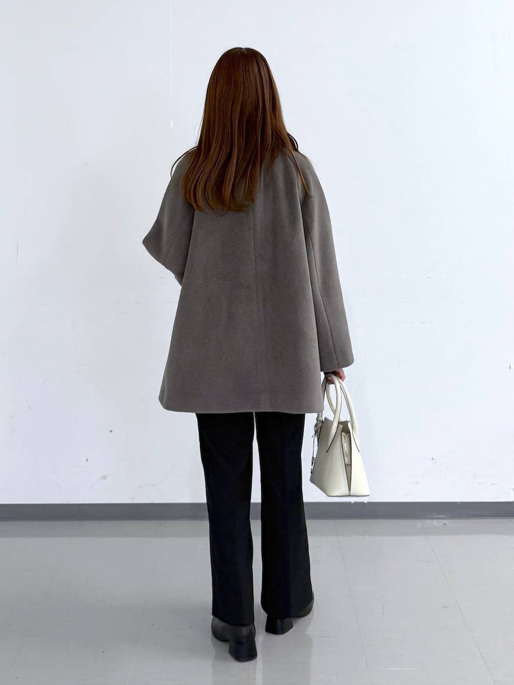 ホワイト系のショルダーバッグ、ブラウン系のチェスターコート、ブラウン系のニット/セーターを着用したレディースの冬コーディネートの3枚目の写真