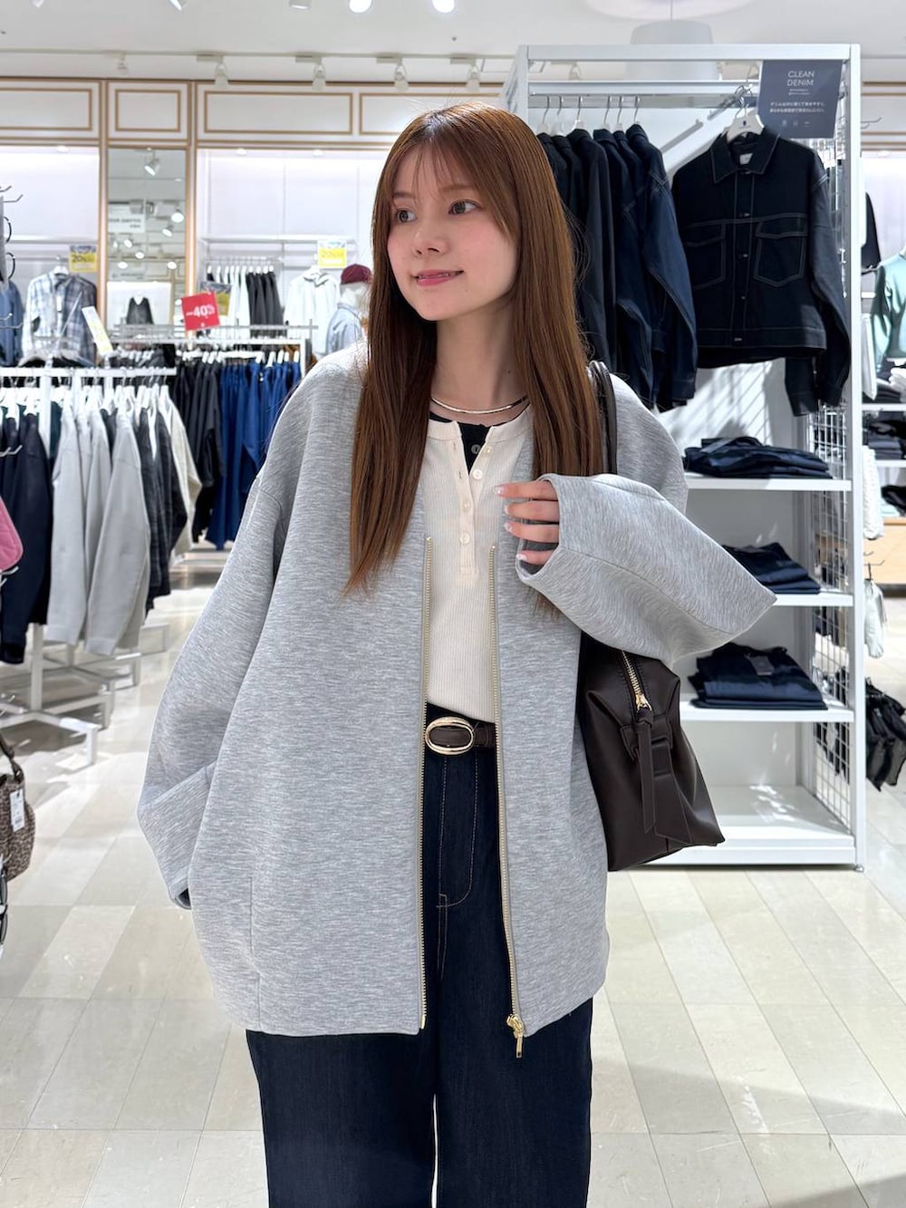 ブラウン系のボストンバッグ、ブルー系のデニムパンツ、グレー系のブルゾンを着用したレディースの春コーディネートの6枚目の写真