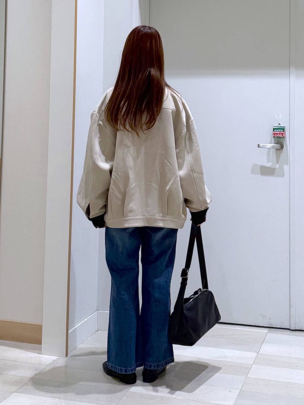 ブラック系のローファー、ブルー系のデニムパンツ、ブラック系のショルダーバッグを着用したレディースの春コーディネートの3枚目の写真