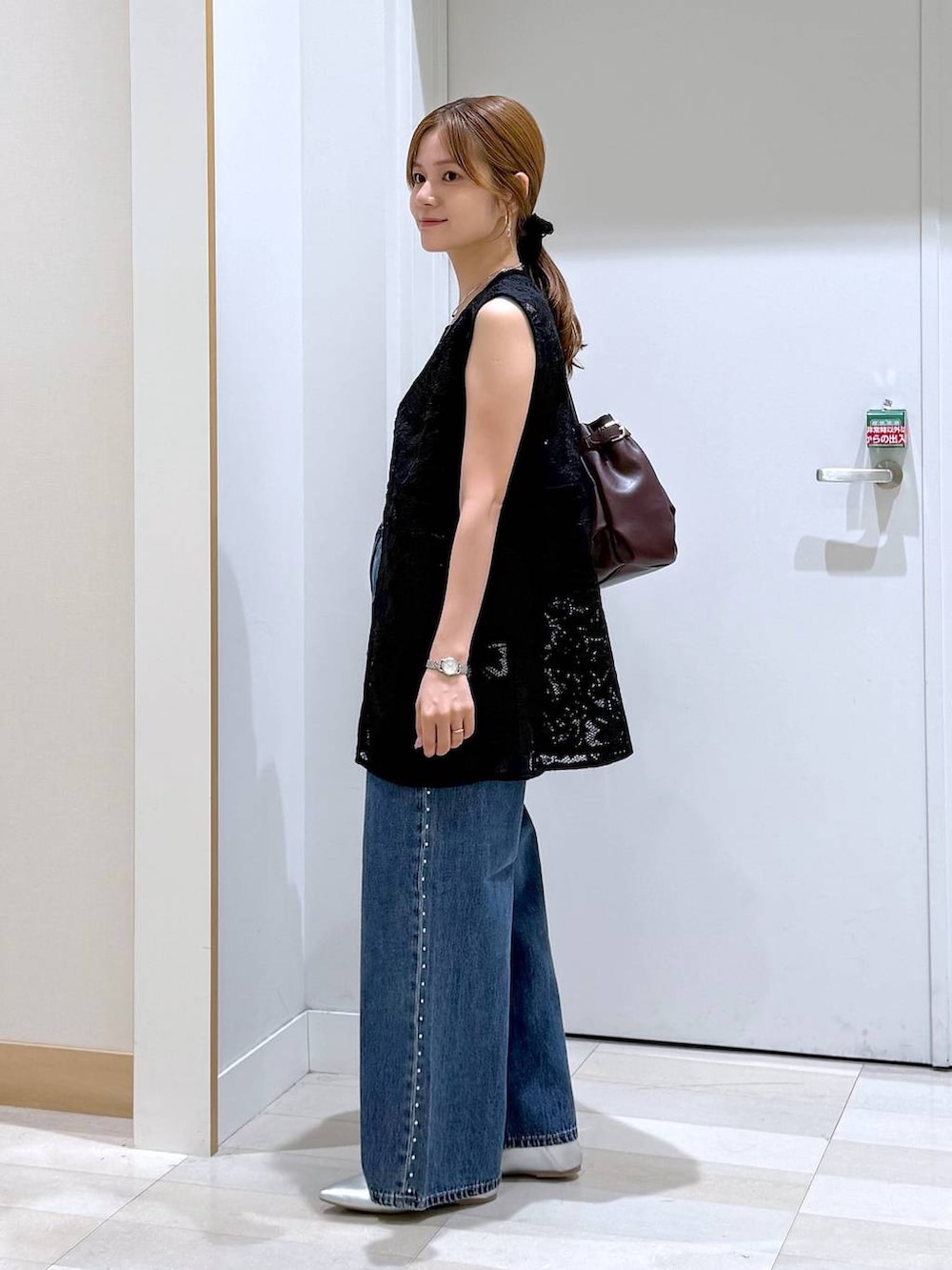 ブルー系のデニムパンツ、レッド系のボストンバッグ、ブラック系のベストを着用したレディースの夏コーディネートの2枚目の写真