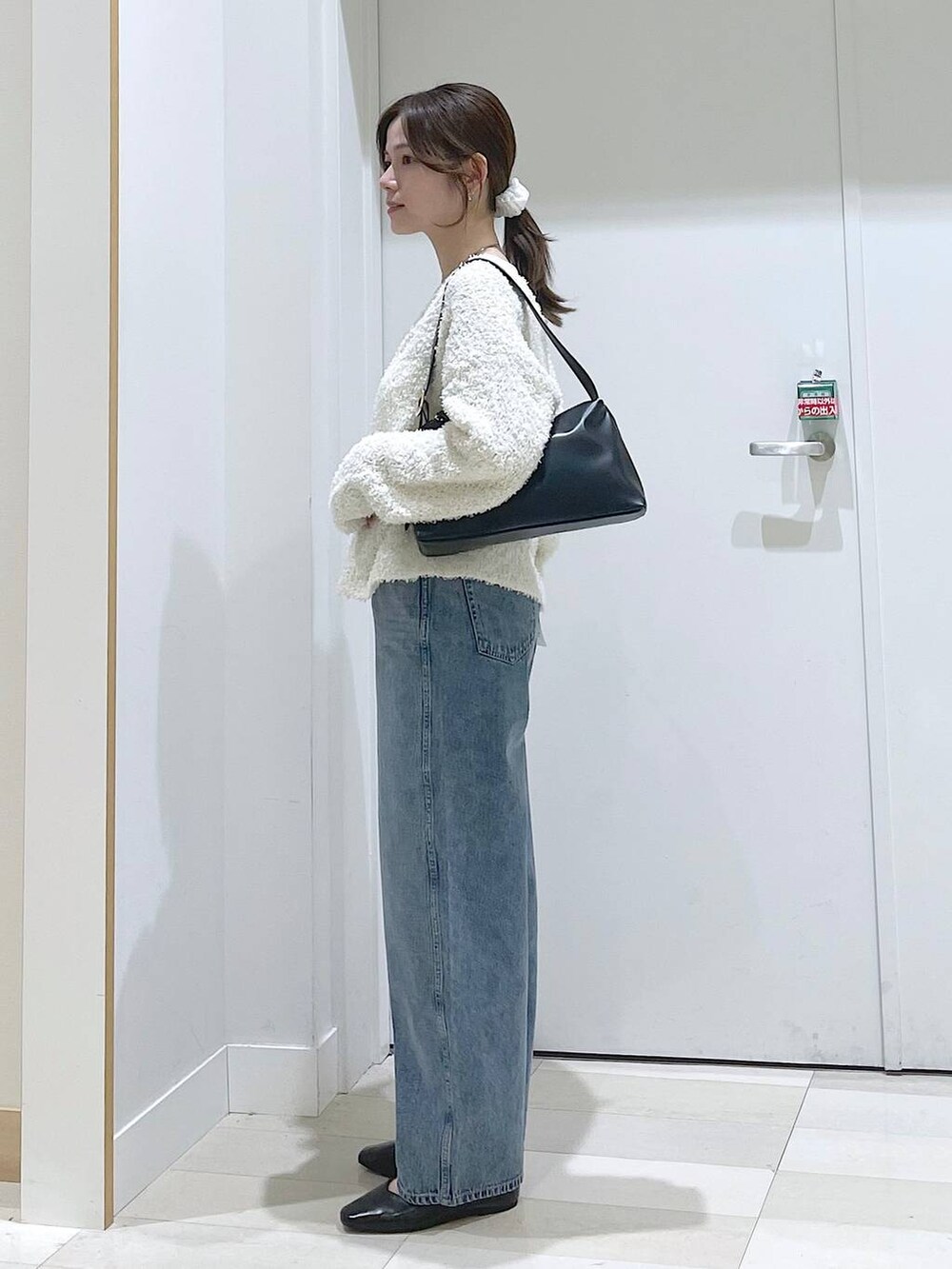 ブルー系のデニムパンツ、ブラック系のパンプス、ブラック系のショルダーバッグを着用したレディースの春コーディネートの2枚目の写真