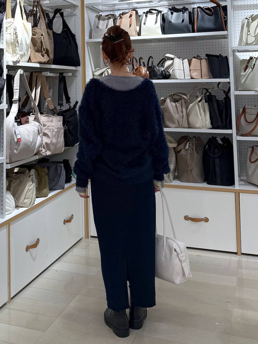 ブラック系のダウンジャケット/コート、ホワイト系のボストンバッグ、ブルー系のワンピースを着用したレディースの冬コーディネートの3枚目の写真