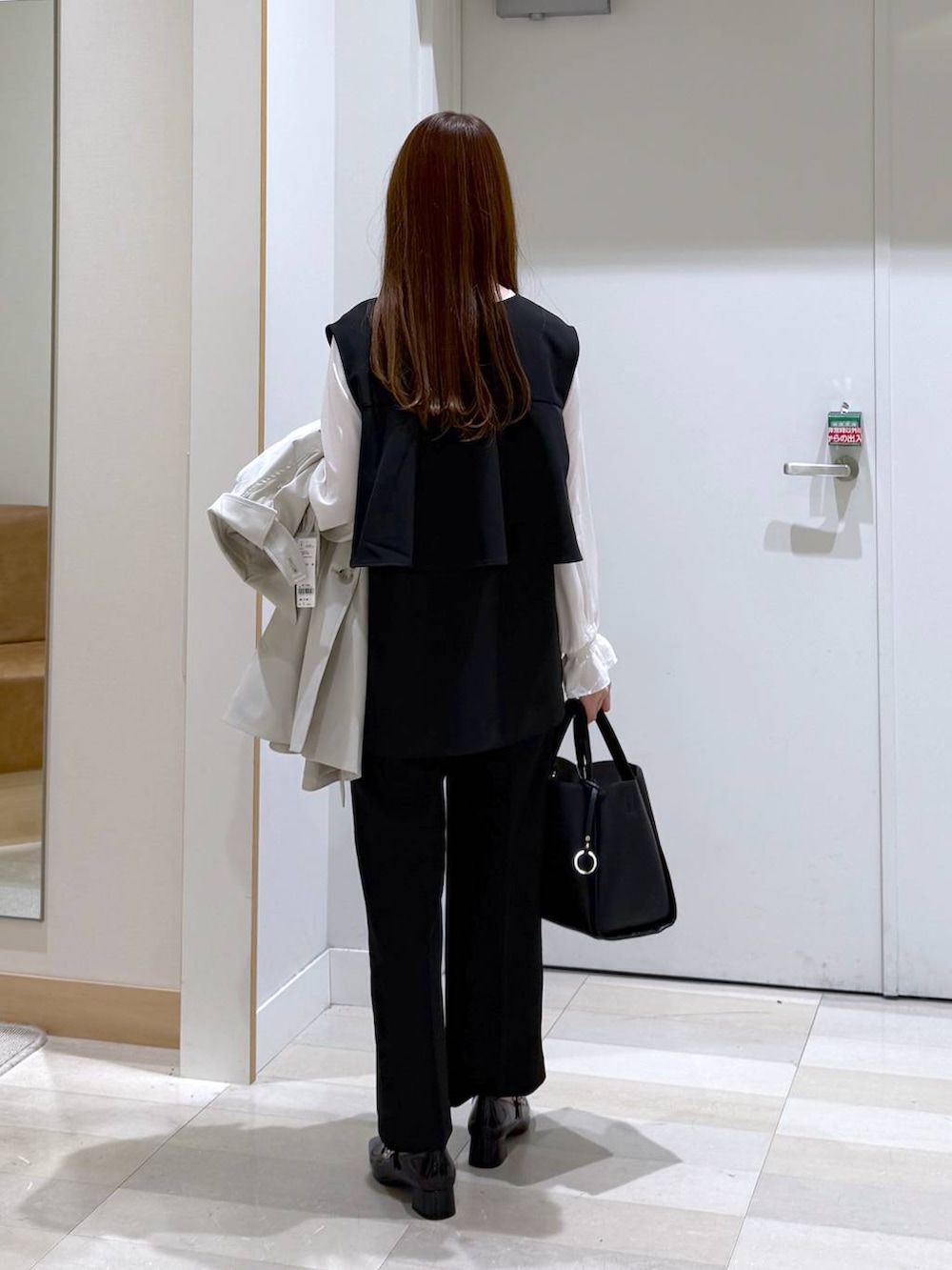 ブラック系のトートバッグ、ブラック系のセットアップ、ベージュ系のトレンチコートを着用したレディースの冬コーディネートの3枚目の写真