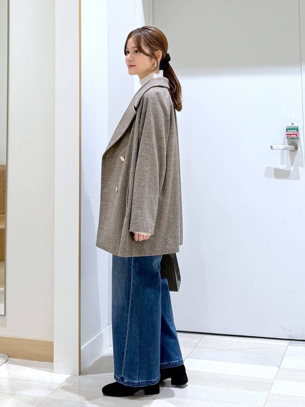 ブラウン系のチェスターコート、グリーン系のショルダーバッグ、ホワイト系のニット/セーターを着用したレディースの秋コーディネートの2枚目の写真