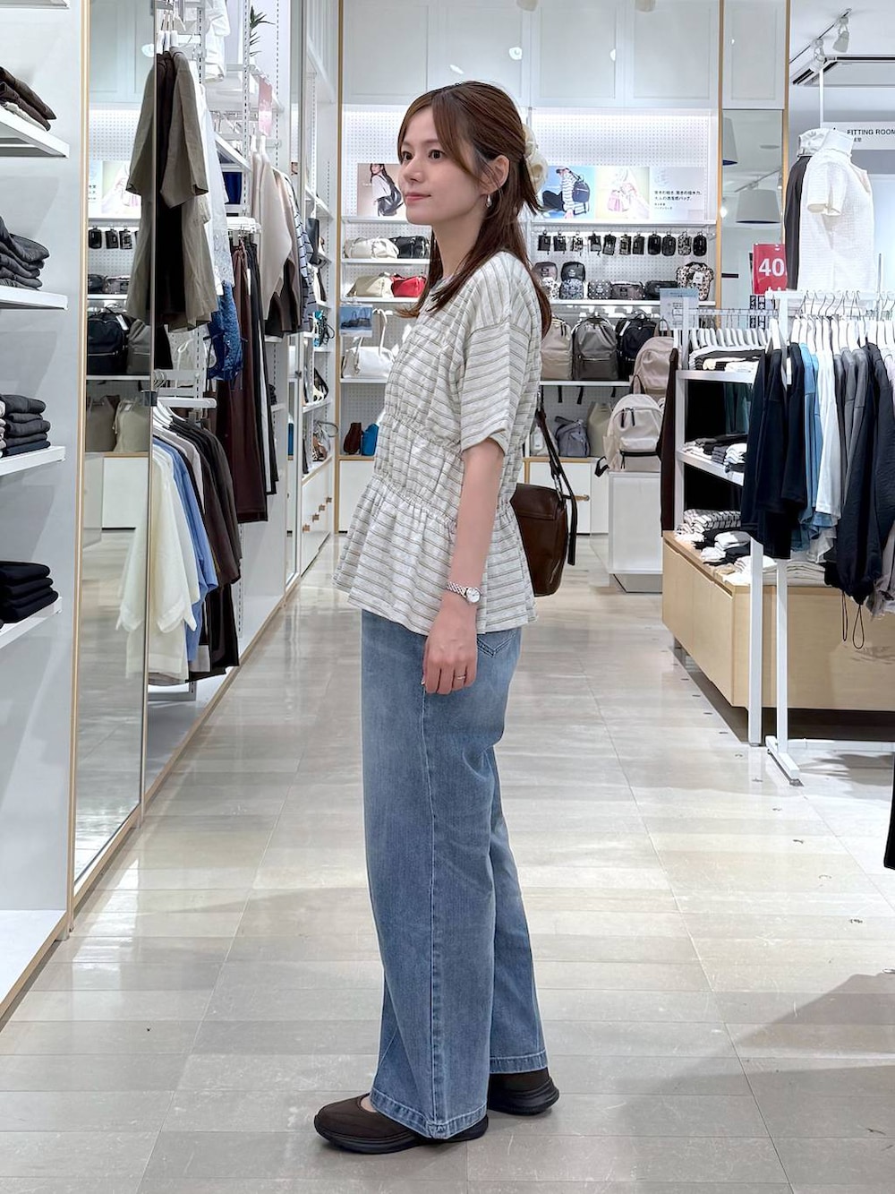 ブルー系のデニムパンツ、ブラウン系のスニーカー、ホワイト系のTシャツ/カットソーを着用したレディースの夏コーディネートの2枚目の写真