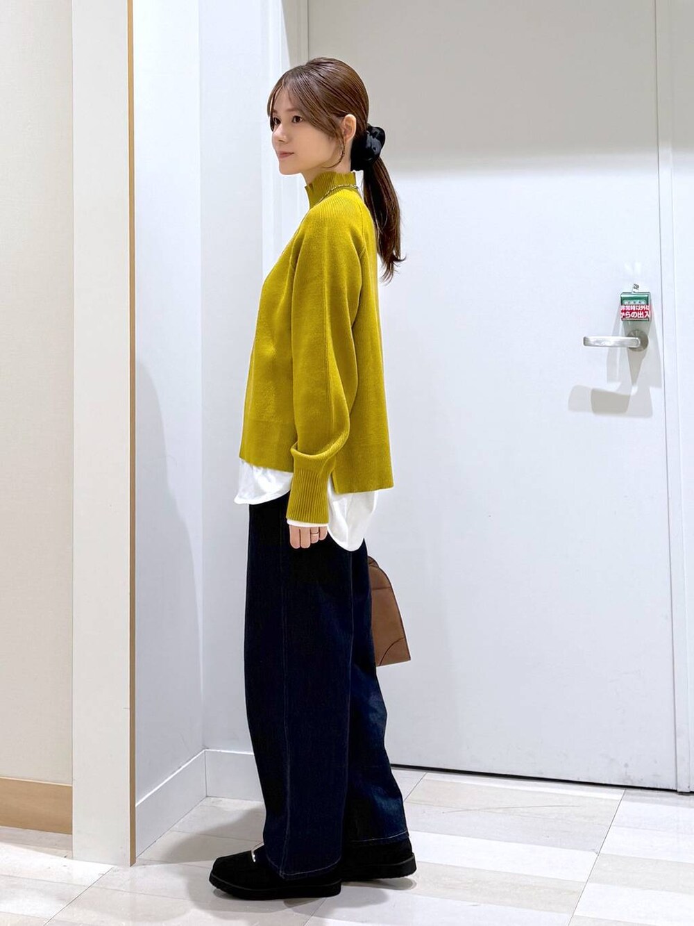 ブラック系のローファー、ブルー系のデニムパンツ、ブラック系のショルダーバッグを着用したレディースの秋コーディネートの2枚目の写真