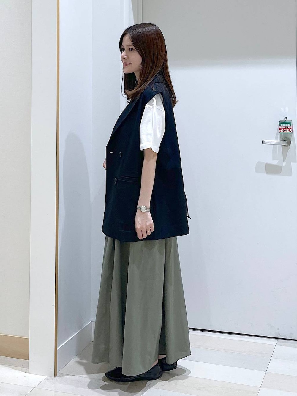 ブラック系のバレエシューズ、ブラック系のベスト、ホワイト系のTシャツ/カットソーを着用したレディースの春コーディネートの2枚目の写真