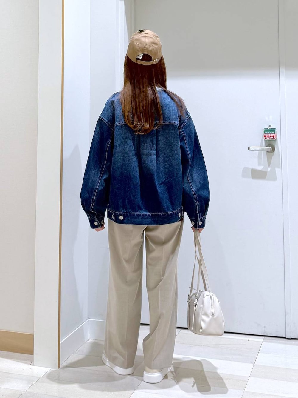 ベージュ系のスラックス、ブルー系のデニムジャケット、ベージュ系のショルダーバッグを着用したレディースの冬コーディネートの3枚目の写真